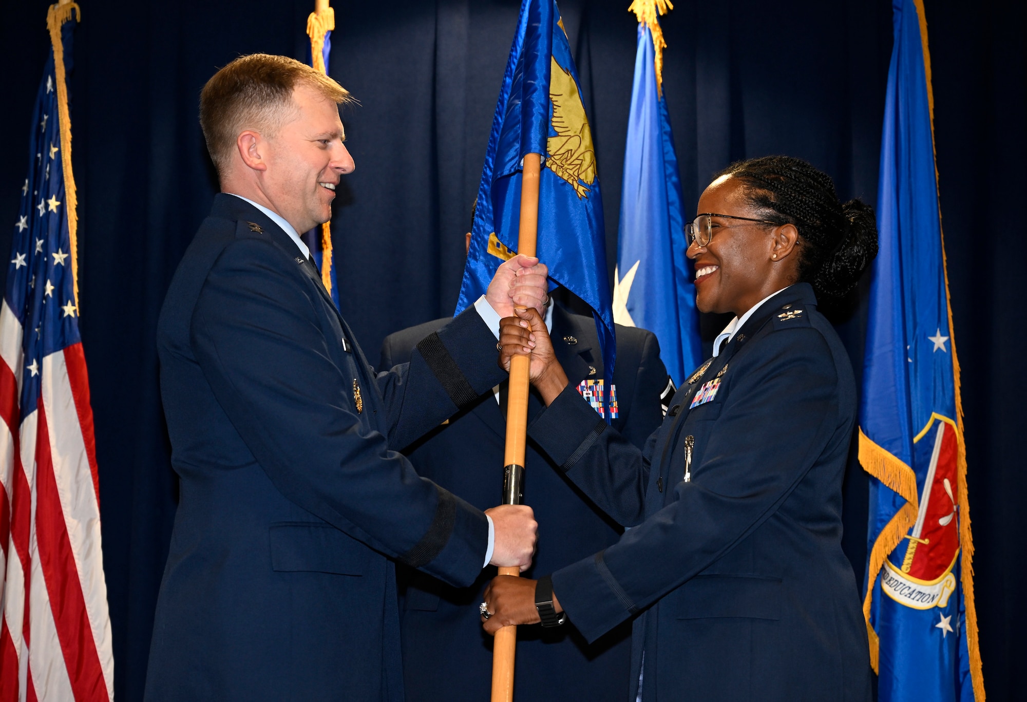 Maj. Gen. Parker H. Wright, commander of the Curtis E. LeMay Center for Doctrine Development and Education, passes the Thomas N. Barnes Center for Enlisted Education flag to Col. Stephanie Q. Wilson during an Assumption of Command ceremony at Maxwell Air Force Base, Alabama, July 14, 2025. (U.S. Air Force photo by Brian Ferguson)