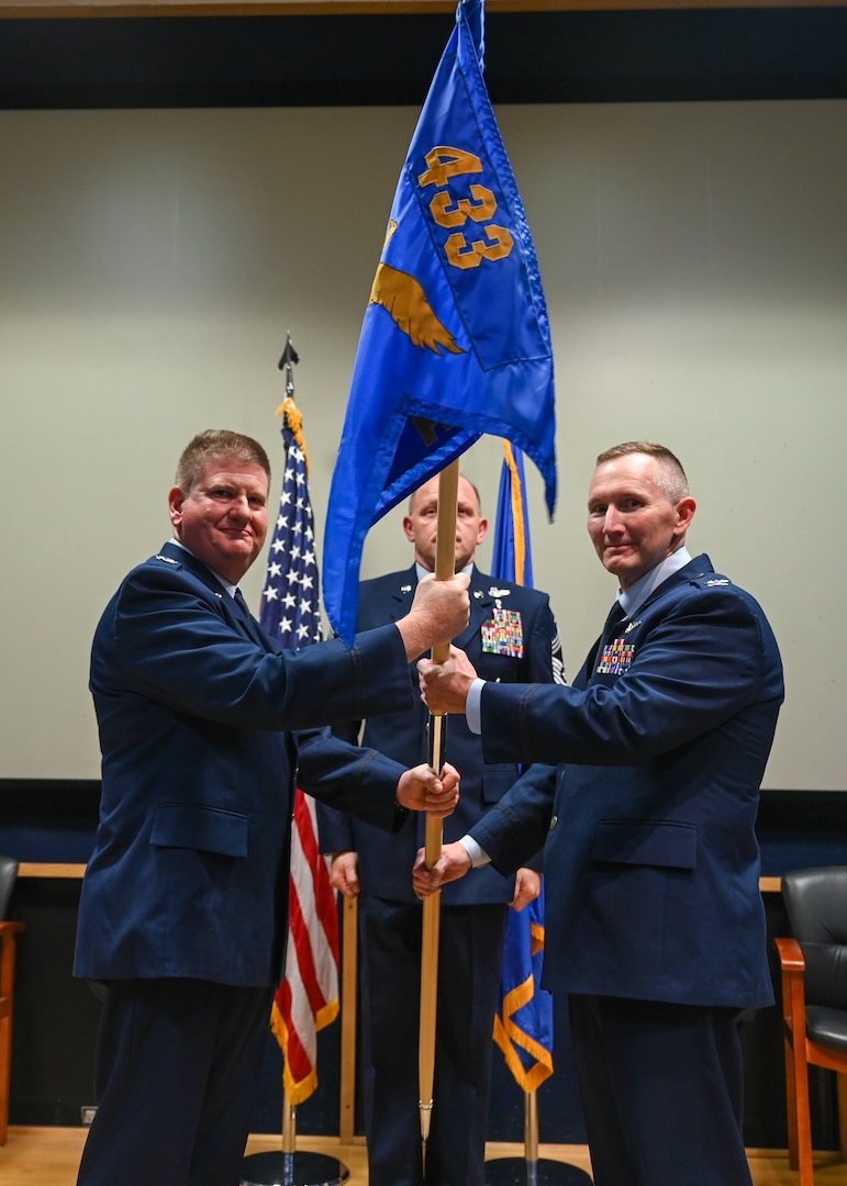 Col. Jeremy Patrick (left), 433rd Operations Group commander, hands the 433rd Aeromedical Evacuation Squadron guidon to Col. David Bailey (right), 433rd AES Commander, during an assumption of command ceremony at Joint Base San Antonio-Lackland, Texas, July 12, 2025.