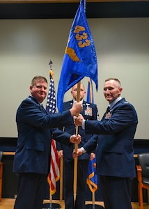 Col. Jeremy Patrick (left), 433rd Operations Group commander, hands the 433rd Aeromedical Evacuation Squadron guidon to Col. David Bailey (right), 433rd AES Commander, during an assumption of command ceremony at Joint Base San Antonio-Lackland, Texas, July 12, 2025.