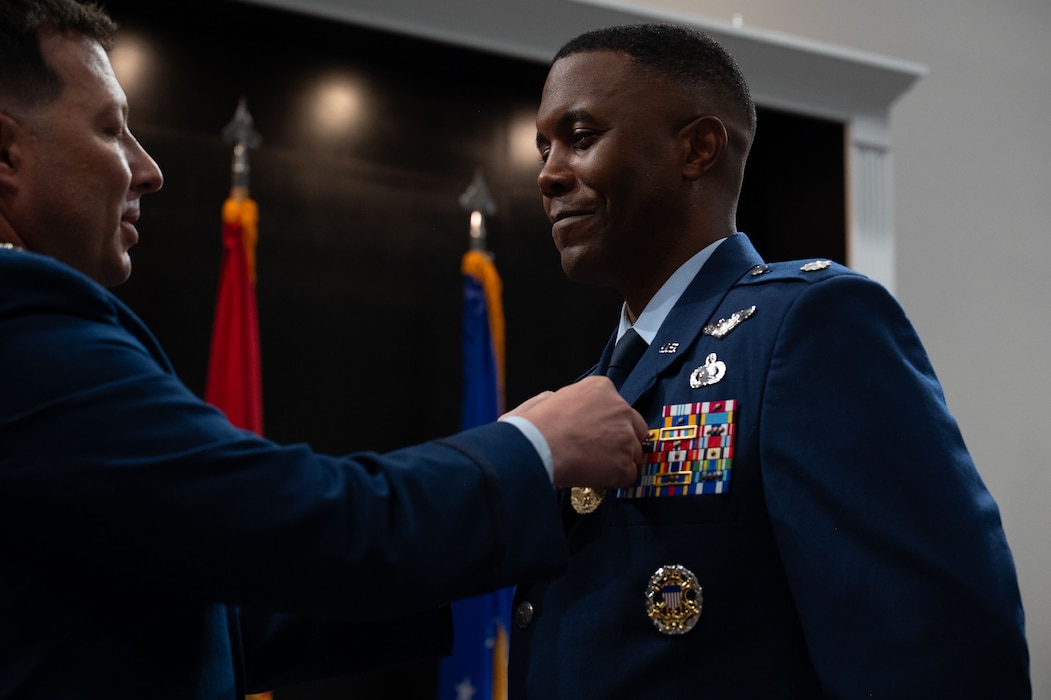 U.S. Air Force Col. Jason Gerber, 17th Training Group commander, pins the Meritorious Service Medal on Lt. Col. Jahmil Edwards, outgoing 316th Training Squadron commander, during the change of command ceremony at the Powell Event Center, Goodfellow Air Force Base, Texas, July 11, 2025. Edwards led the DoD’s largest joint cryptologic training squadron, spear-headed a 3 million dollar initiative with the U.S. Army to develop the Air Education and Training Command’s first joint signals intelligence training environment and led the squadron on the National Security Agency’s priority modernization list. (U.S. Air Force photo by Airman 1st Class Brian Lummus)