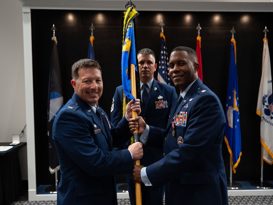 U.S. Air Force Lt. Col. Jahmil Edwards, outgoing 316th Training Squadron commander, passes the guidon to Col. Jason Gerber, 17th Training Group commander, relinquishing command during the change of command ceremony at the Powell Event Center, Goodfellow Air Force Base, Texas, July 11, 2025. Passing the guidon represents the transfer of leadership responsibilities to the next commander. (U.S. Air Force photo by Airman 1st Class Brian Lummus)