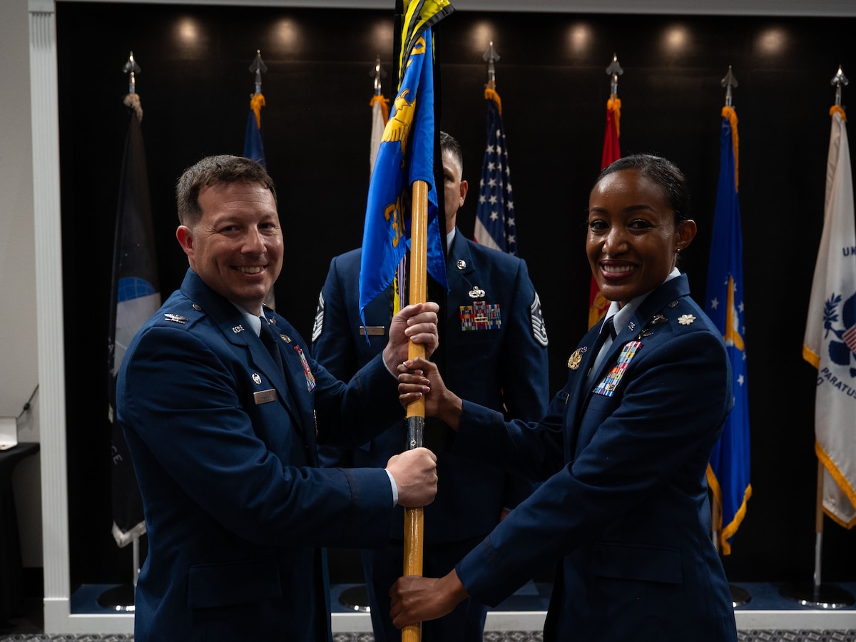 U.S. Air Force Col. Jason Gerber, 17th Training Group commander, passes the guidon to Lt. Col. Bryanna McQueen, 316th Training Squadron commander, during the change of command ceremony at the Powell Event Center, Goodfellow Air Force Base, Texas, July 11, 2025. The passing of the guidon is a military tradition that dates back to the time of Frederick the Great of Prussia. (U.S. Air Force photo by Airman 1st Class Brian Lummus)