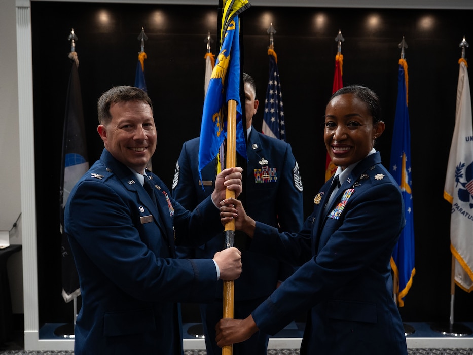 U.S. Air Force Col. Jason Gerber, 17th Training Group commander, passes the guidon to Lt. Col. Bryanna McQueen, 316th Training Squadron commander, during the change of command ceremony at the Powell Event Center, Goodfellow Air Force Base, Texas, July 11, 2025. The passing of the guidon is a military tradition that dates back to the time of Frederick the Great of Prussia. (U.S. Air Force photo by Airman 1st Class Brian Lummus)