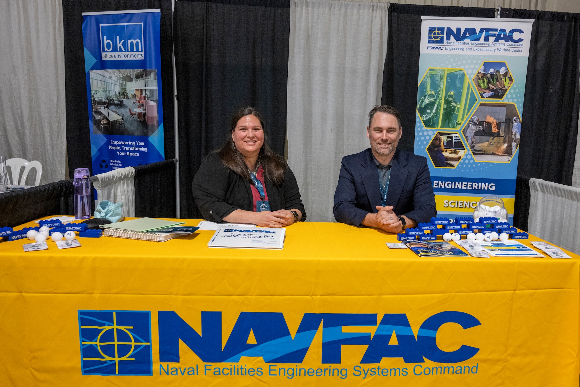 Two people sit at NAVFAC EXWC information table