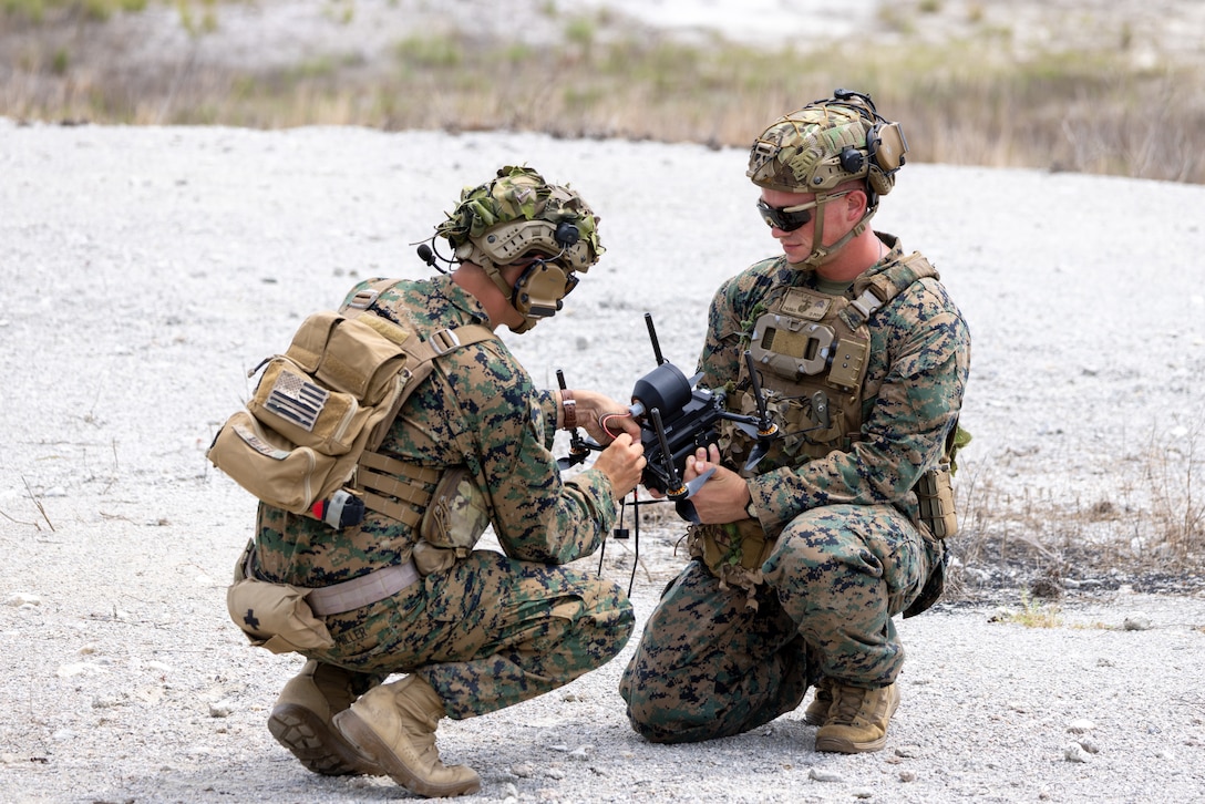 U.S. Marine Corps Staff Sgt. Kaleb Miller, left, an instructor with Advanced Infantry Training Battalion, School of Infantry – East, and a native of Pennsylvania, and Sgt. Caleb Woelk, right, an instructor with AITB, SOI-E, and a native of Virginia, connect a Terminus anti-personnel munition to a Neros Archer small unmanned aircraft system (SUAS) in preparation for a combined arms live-fire training exercise involving the employment of small unmanned aircraft systems (SUAS) to deliver munitions on designated targets at Camp Lejeune, North Carolina, July 2, 2025. This event marked the first time munitions were employed from SUAS during a live-fire training exercise on Camp Lejeune, demonstrating the capability of integrating aerial strike capabilities at the tactical level. (U.S. Marine Corps photo by Cpl. Zachariah Ferraro)