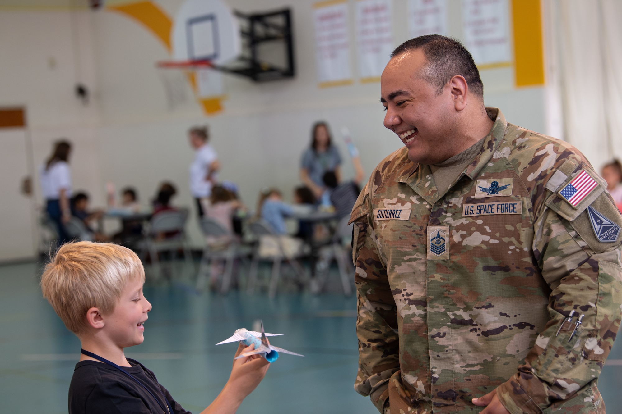 U.S. Space Force Master Sgt. Paul Gutierrez, U.S. Space Forces-Japan missile warning advisor, speaks with a student from Yokota West Elementary School during the Space Systems Command STEM outreach day at Yokota Air Base, Japan, May 15, 2025. SSC’s outreach connects students with real-world space applications, strengthening public understanding of space missions and the U.S. Space Force’s role in national defense. (U.S. Air Force photo by Airman 1st Class David S. Calcote)