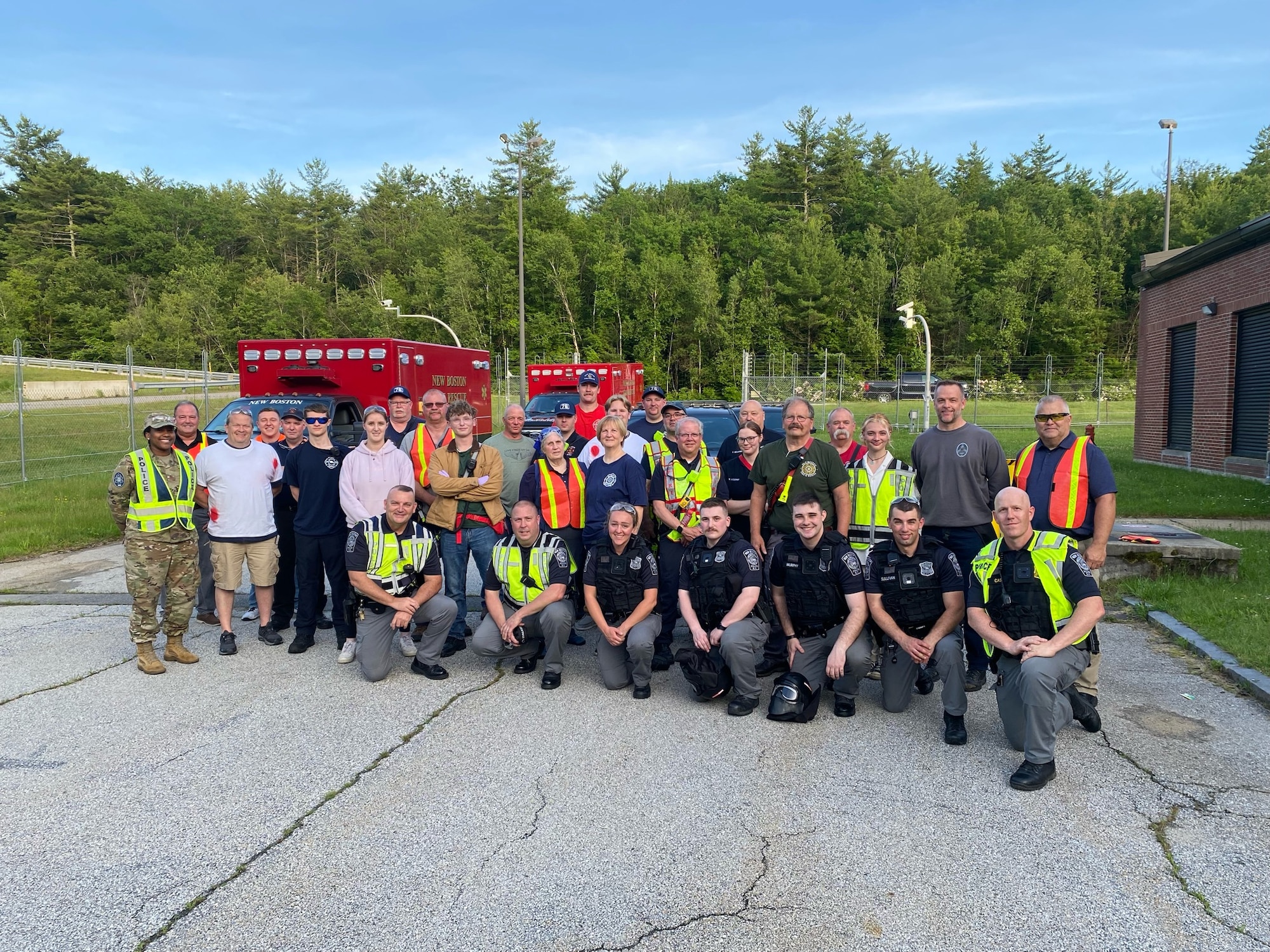 Many people stand in front of emergency vehicles for a group photo
