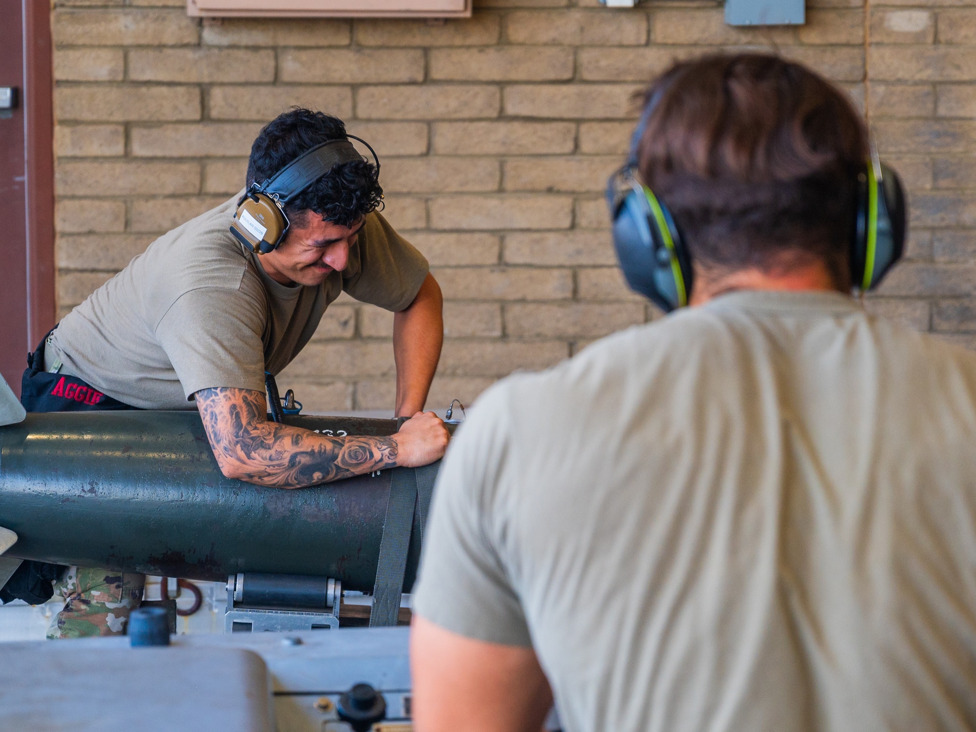 U.S. Air Force Staff Sgt Aaron Aguilar (rear), 56th Aircraft Maintenance Squadron weapons load team member, secures training ordnance to a MJU-1 Lift Truck operated by Senior Airman Mark Anthony Colon, 62rd Aircraft Maintenance Unit weapons load team member, during the 56th Fighter Wing’s third quarterly load competition, July 11, 2025, at Luke Air Force Base, Arizona.