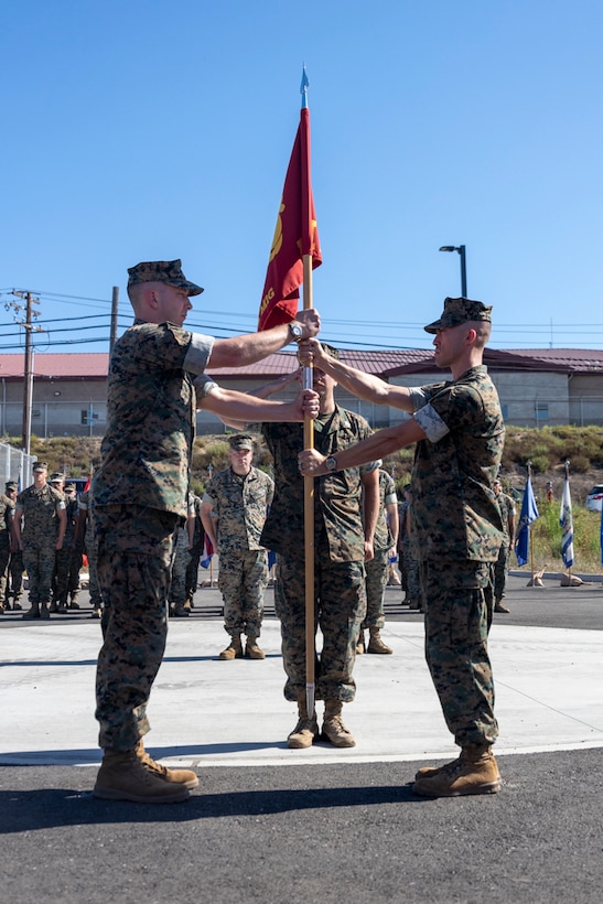 U.S. Marine Corps Maj. David M. Brennan, right, the outgoing commander of Headquarters Company, I Marine Expeditionary Force Information Group, passes the company guidon to Maj. Adam S. Jatho, the incoming commander, representing the passing of authority during the Headquarters Company change of command ceremony at Marine Corps Base Camp Pendleton, California, July 9, 2025. (U.S. Marine Corps photo by Cpl. Brandon Marrero)