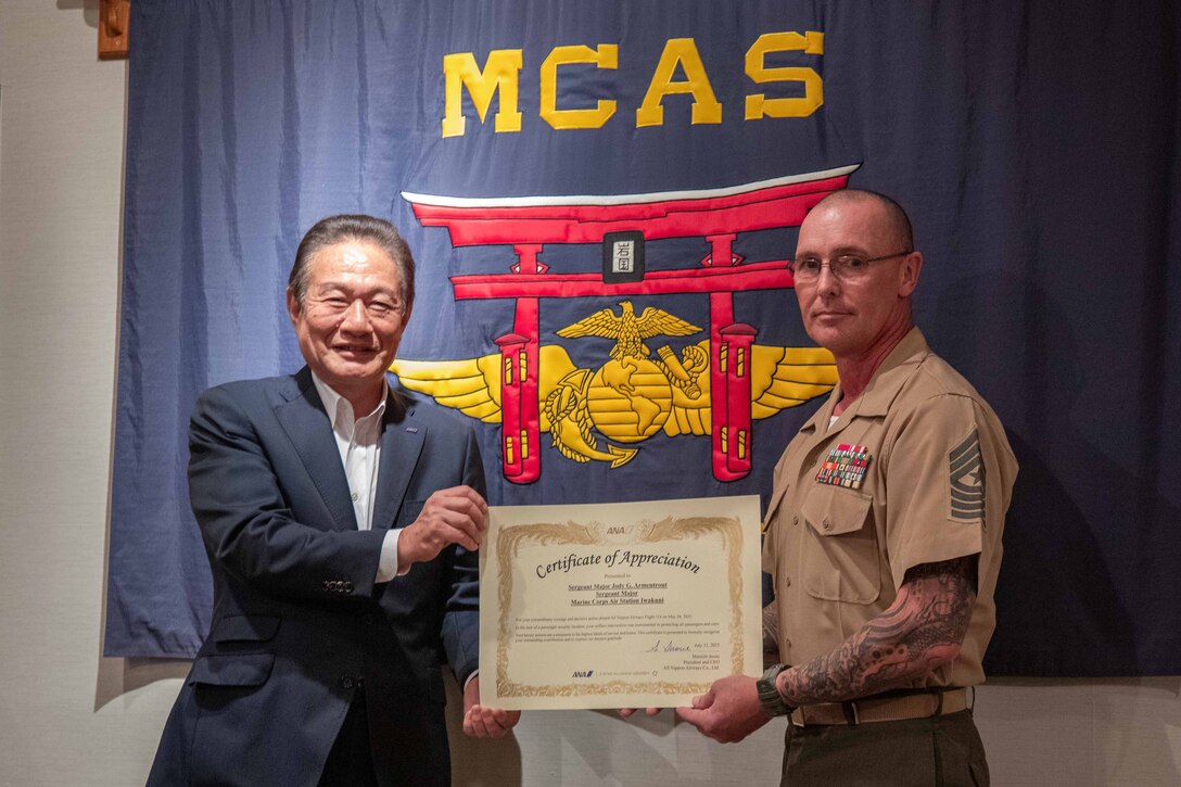 U.S. Marine Corps. Sgt. Maj. Jody Armentrout, right, sergeant major of Marine Corps Air Station Iwakuni, a native of Abilene, Texas, and Mr. Shinichi Inoue, the President and CEO of All Nippon Airways, pose for a photo at MCAS Iwakuni, Japan, July 11, 2025. Representatives for All Nippon Airways presented U.S. Marine Corps Sgt. Maj. Armentrout with a certificate of appreciation for his actions on May 24th, 2025, when he subdued a disruptive passenger who attempted to open an exit door during a flight. (U.S. Marine Corps photo by Lance Cpl. Donald Dugger)