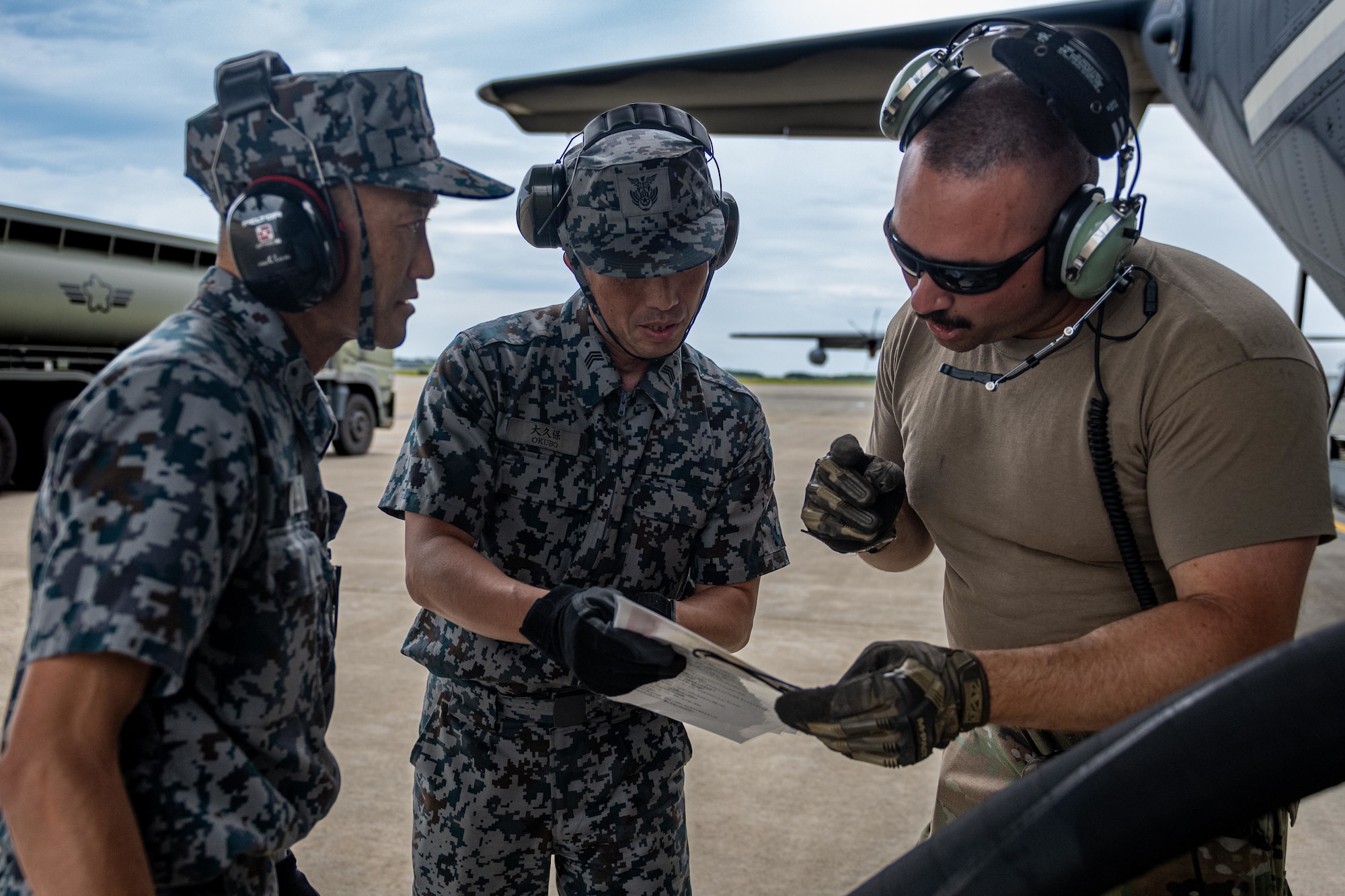 U.S. Air Force Master Sgt. Jordan Benshoof, right, 129th Aircraft Maintenance Squadron crew chief lead, indicates the amount of Jet A-1 fuel needed for a U.S. Air Force C-130J Super Hercules to Japan Air Self-Defense Force petroleum, oil, and lubricant specialists during exercise Resolute Force Pacific (REFORPAC) 2025.