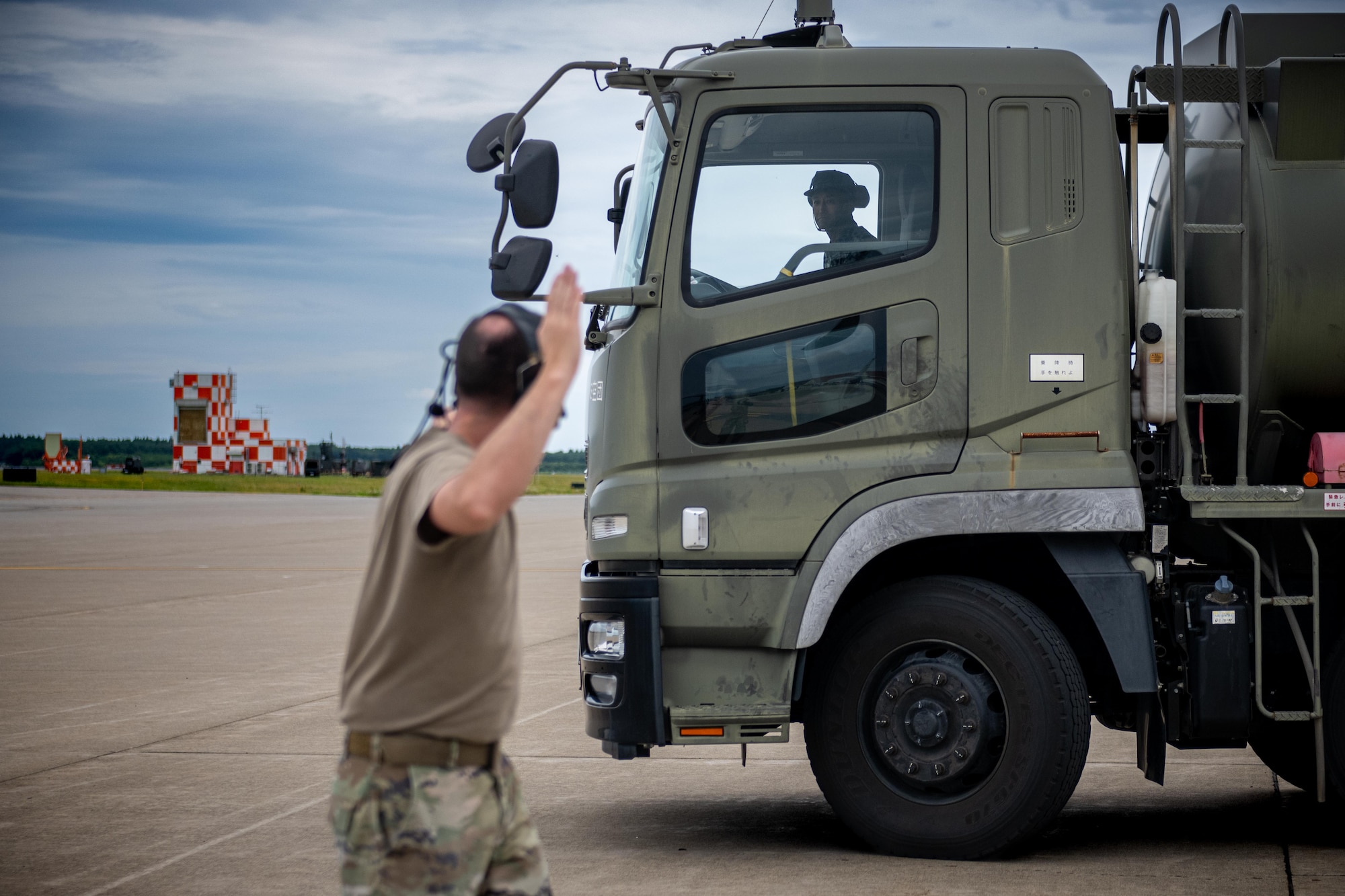 U.S. Air Force Master Sgt. Jordan Benshoof, 129th Aircraft Maintenance Squadron crew chief lead, marshals in a Japan Air Self-Defense Force refueling truck during exercise Resolute Force Pacific 2025.