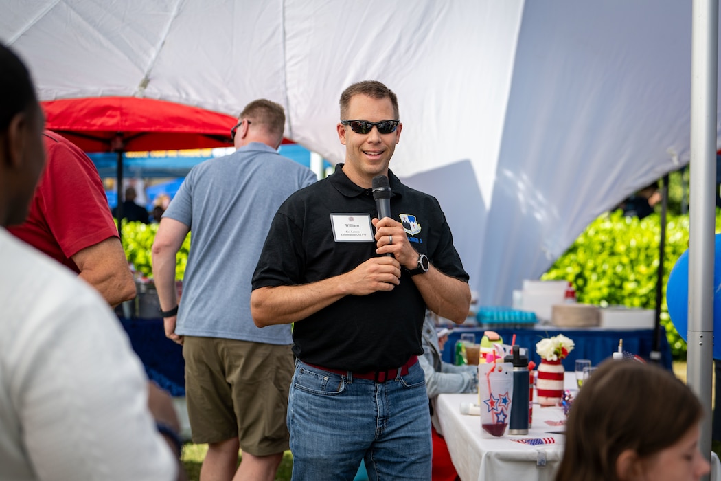 A man speaks into a microphone in front of a crowd.