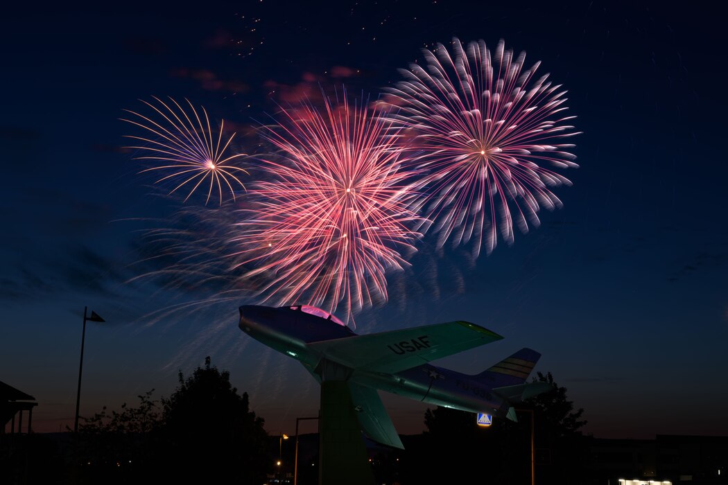 Fireworks in night sky over static jet display.