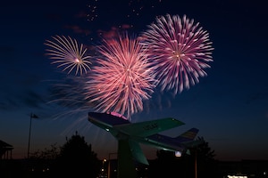 Fireworks in night sky over static jet display.