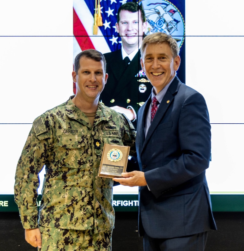 two men hold an award.