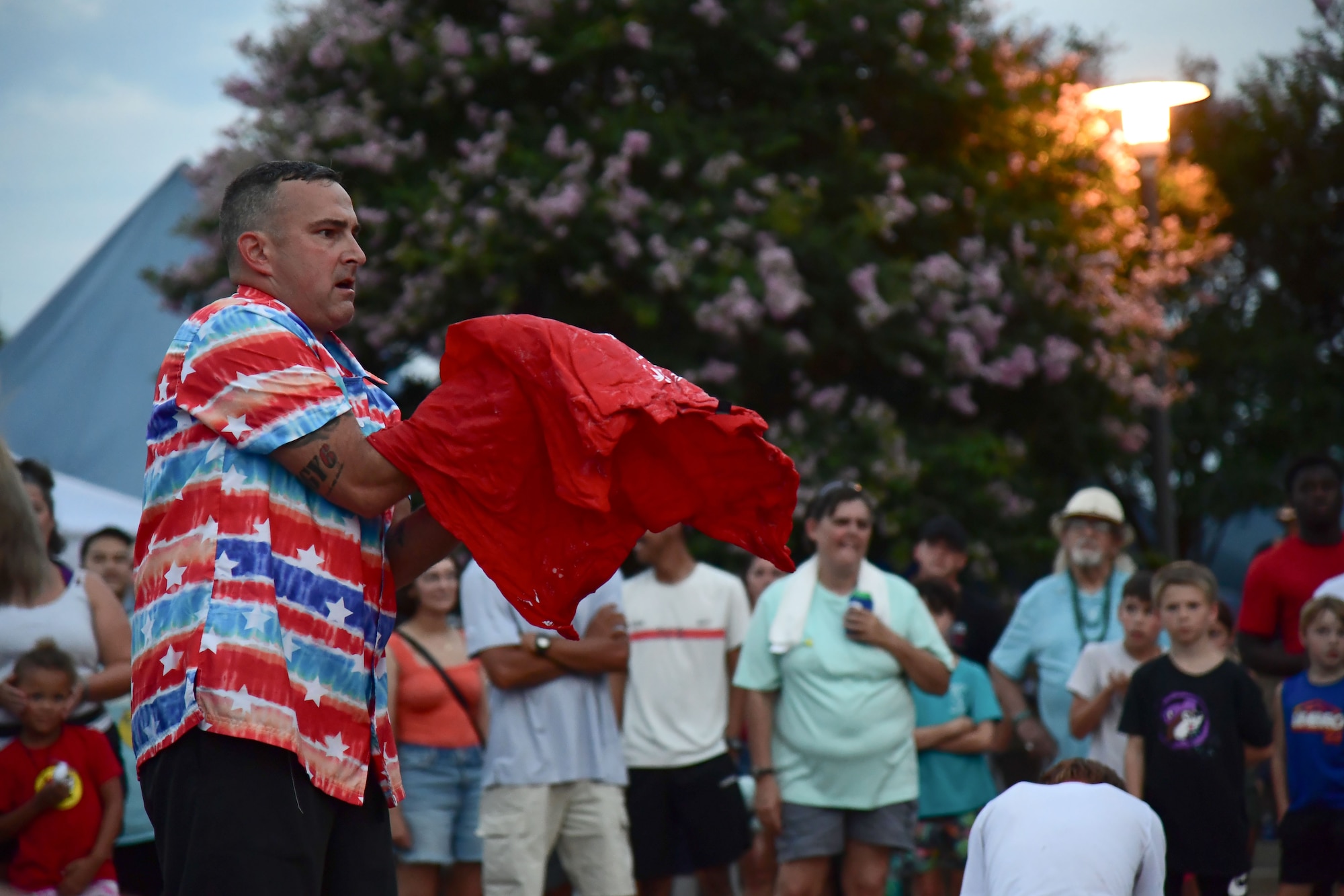 : A man puts his arms into a red shirt in front of a crowd