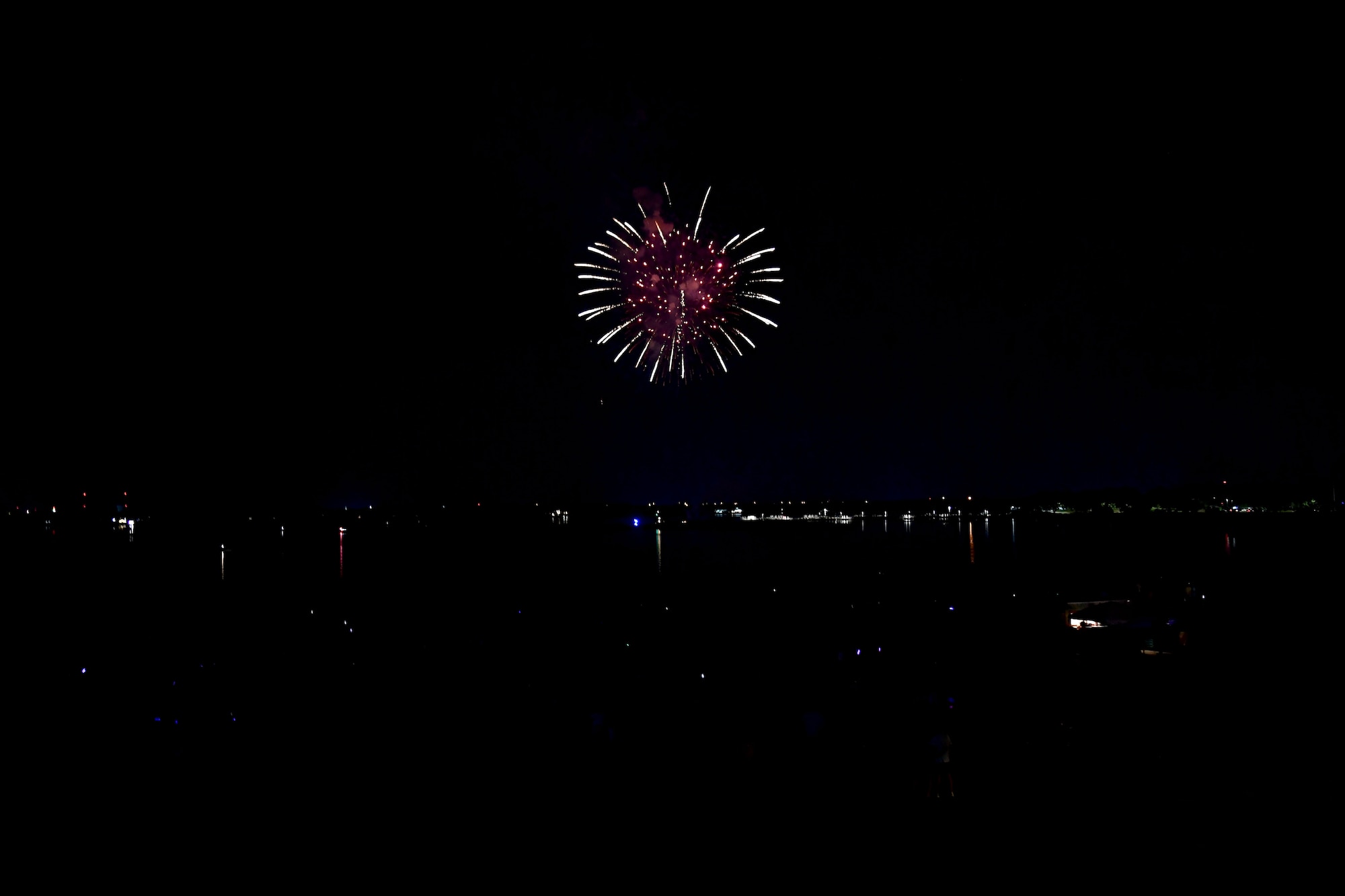 A firework fills the sky over water at night