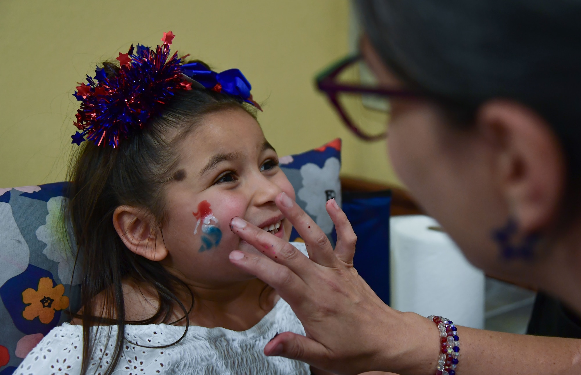 A woman applies paint to a young girl’s face