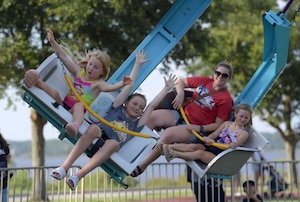 children and their mother sit on a carnival ride