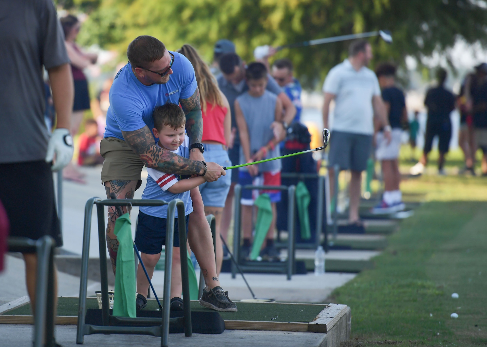 A man helps a young boy swing a golf club