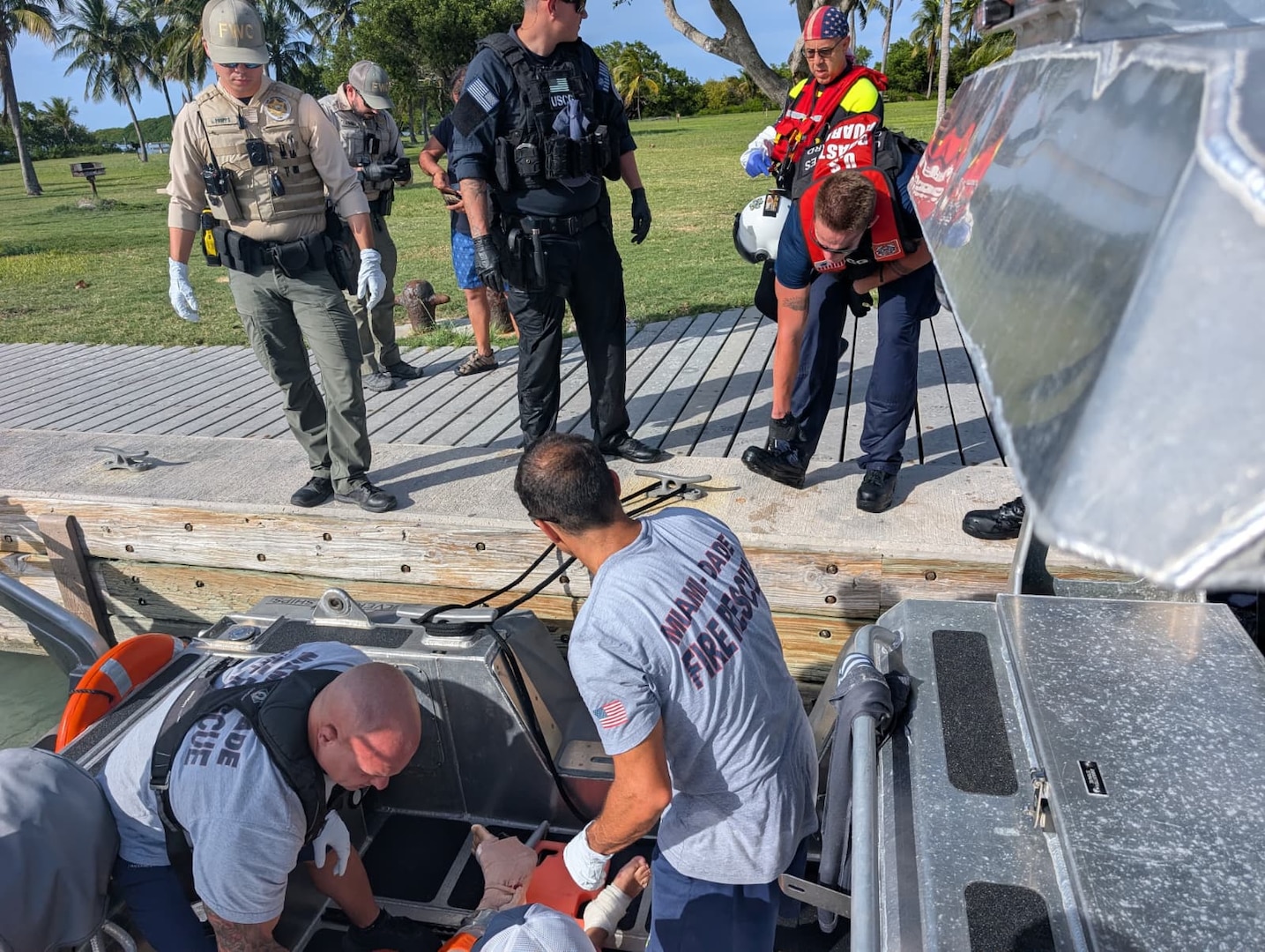 Crew members from U.S. Coast Guard Station Miami Beach and Maritime Safety and Security Team provide first aid to a man who suffered a severe leg injury after being struck by a boat propeller, near Elliot Key, July 15, 2025. The man was taken to the Jackson South Medical Center for a higher level of care. (U.S. Coast Guard Photo)