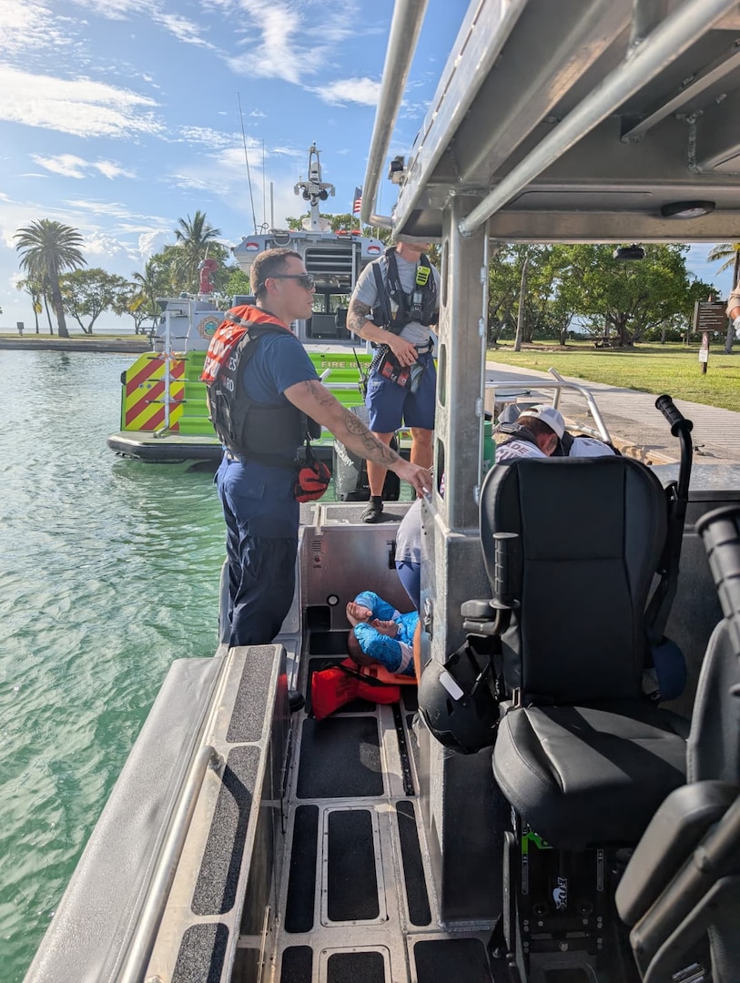 Crew members from U.S. Coast Guard Station Miami Beach and Maritime Safety and Security Team provide first aid to a man who suffered a severe leg injury after being struck by a boat propeller, near Elliot Key, July 15, 2025. The man was taken to the Jackson South Medical Center for a higher level of care. (U.S. Coast Guard Photo)