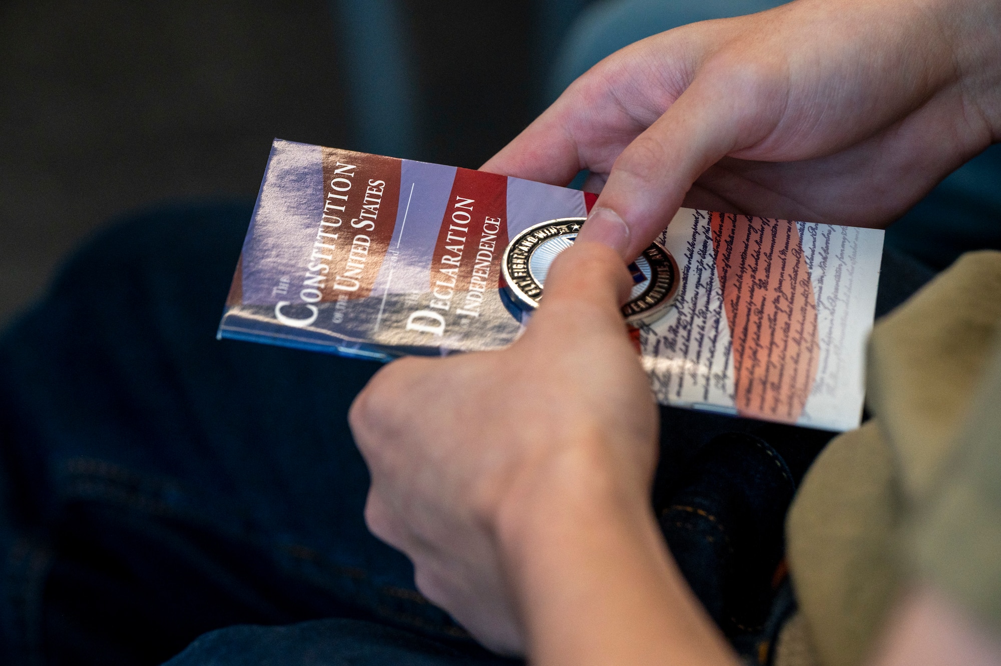 A delayed entry program recruit holds a copy of the U.S. Constitution and a challenge coin during an enlistment ceremony at the Air & Space Forces Association headquarters in Arlington, Va., July 11, 2025. The delayed entry program recruits recited a stanza in the oath of enlistment which is to, “support and defend the Constitution of the United States.” (U.S. Air Force photo by Hayden Hallman)