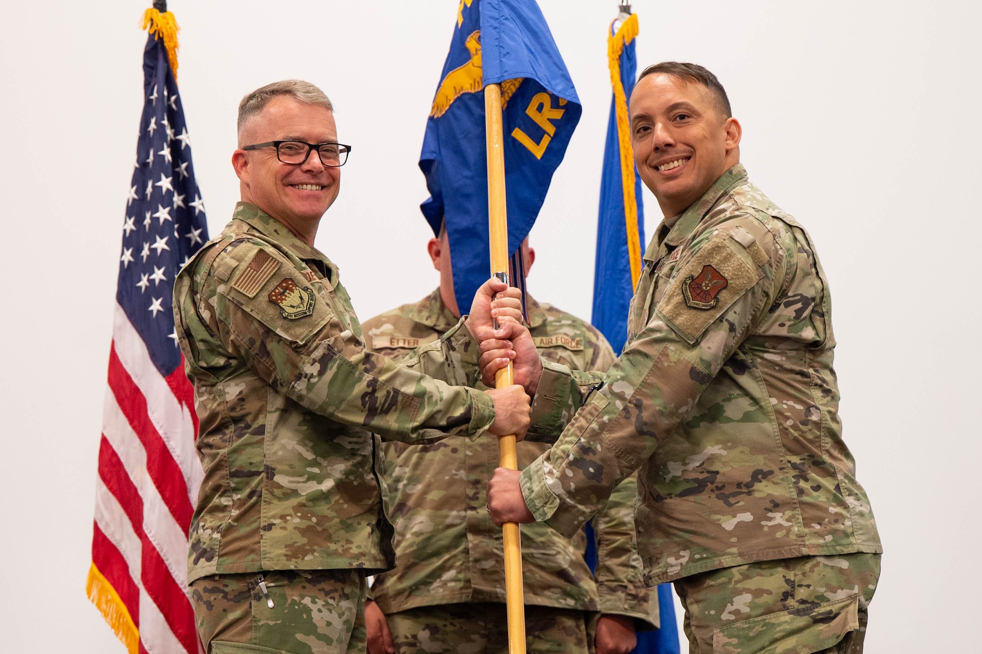 Men in uniform hold a flag.