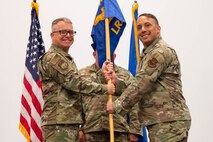 Men in uniform hold a flag.