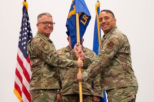 Men in uniform hold a flag.