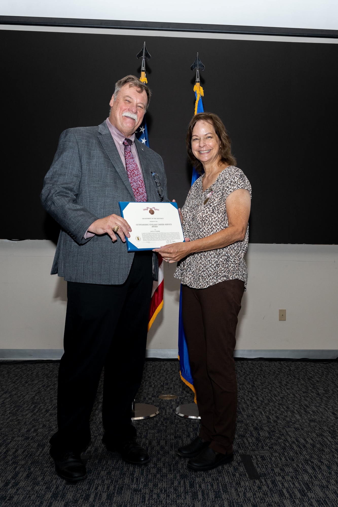 Timothy Ori, executive director of the 37th Training Wing, presents Anita Conder a certificate during her retirement ceremony.