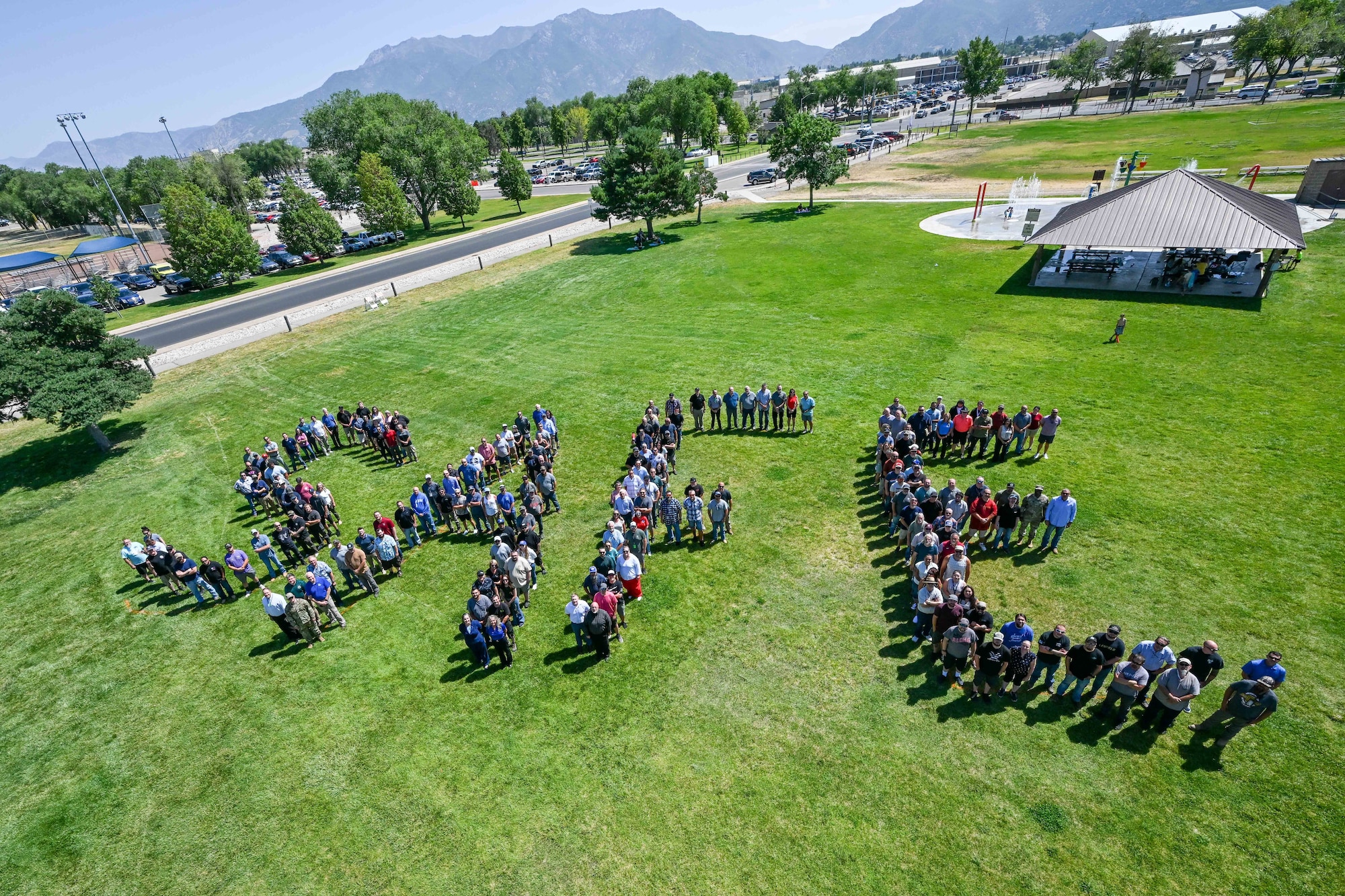 A large group of employees from the 309th Maintenance Support Group stands in a grassy field, arranged to spell the word “SAFE.”