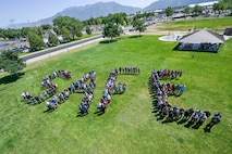 A large group of employees from the 309th Maintenance Support Group stands in a grassy field, arranged to spell the word “SAFE.”