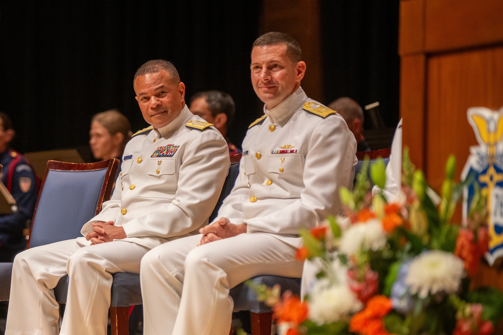 U.S. Coast Guard Academy (USCGA) Superintendent Rear Adm. Gregory Rothrock (right to left) and Rear Adm. Michael sit onstage during a change of command ceremony inside Leamy Hall at USCGA, New London, Connecticut, July 16, 2025. Rothrock relieved Johnston to become the 44th superintendent of USCGA. (U.S. Coast Guard photo by Petty Officer Third Class Leo Avila.)