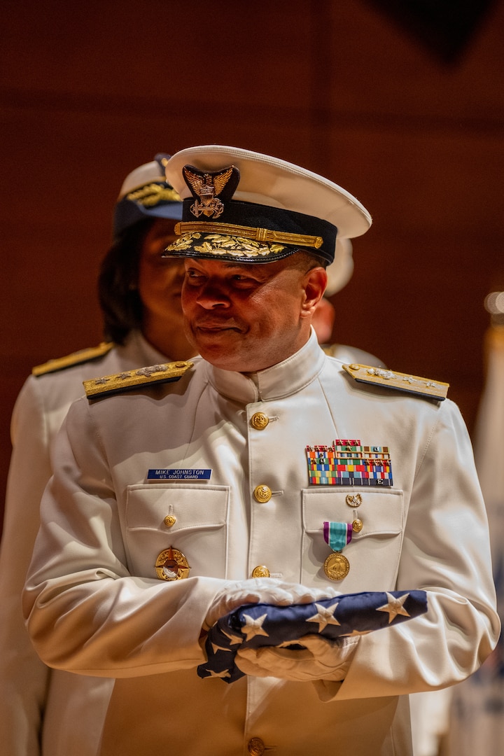 U.S. Coast Guard Rear Adm. Michael Johnston holds a U.S. flag presented to him during his change of command ceremony inside Leamy Hall at the U.S. Coast Guard Academy (USCGA), New London, Connecticut, July 16, 2025. Johnston was relieved by Rear Adm. Gregory Rothrock who became the 44th superintendent of USCGA. (U.S. Coast Guard photo by Petty Officer Third Class Leo Avila.)