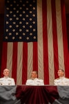 Acting Commandant of the Coast Guard Adm. Kevin Lunday (left to right), Rear Adm. Michael Johnston, and U.S. Coast Guard Academy (USCGA) Superintendent Rear Adm. Gregory Rothrock are seated onstage during a change of command ceremony inside Leamy Hall at USCGA, New London, Connecticut, July 16, 2025. Johnston was relieved by Rothrock who became the 44th superintendent of USCGA. (U.S. Coast Guard photo by Petty Officer Third Class Leo Avila.)