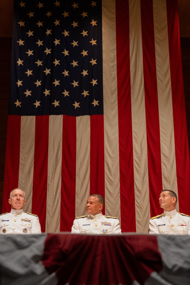 Acting Commandant of the Coast Guard Adm. Kevin Lunday (left to right), Rear Adm. Michael Johnston, and U.S. Coast Guard Academy (USCGA) Superintendent Rear Adm. Gregory Rothrock are seated onstage during a change of command ceremony inside Leamy Hall at USCGA, New London, Connecticut, July 16, 2025. Johnston was relieved by Rothrock who became the 44th superintendent of USCGA. (U.S. Coast Guard photo by Petty Officer Third Class Leo Avila.)