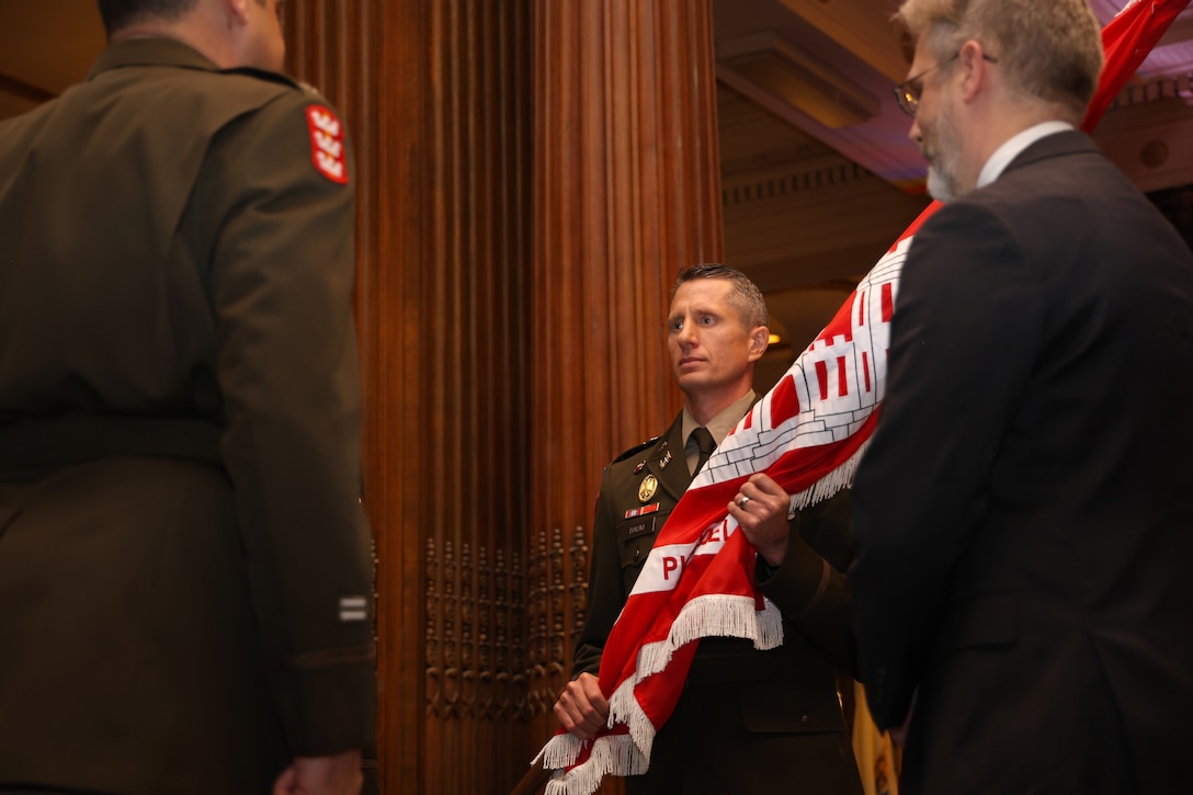 Photo shows a military officer accepting a flag representing the unit colors during a ceremony.