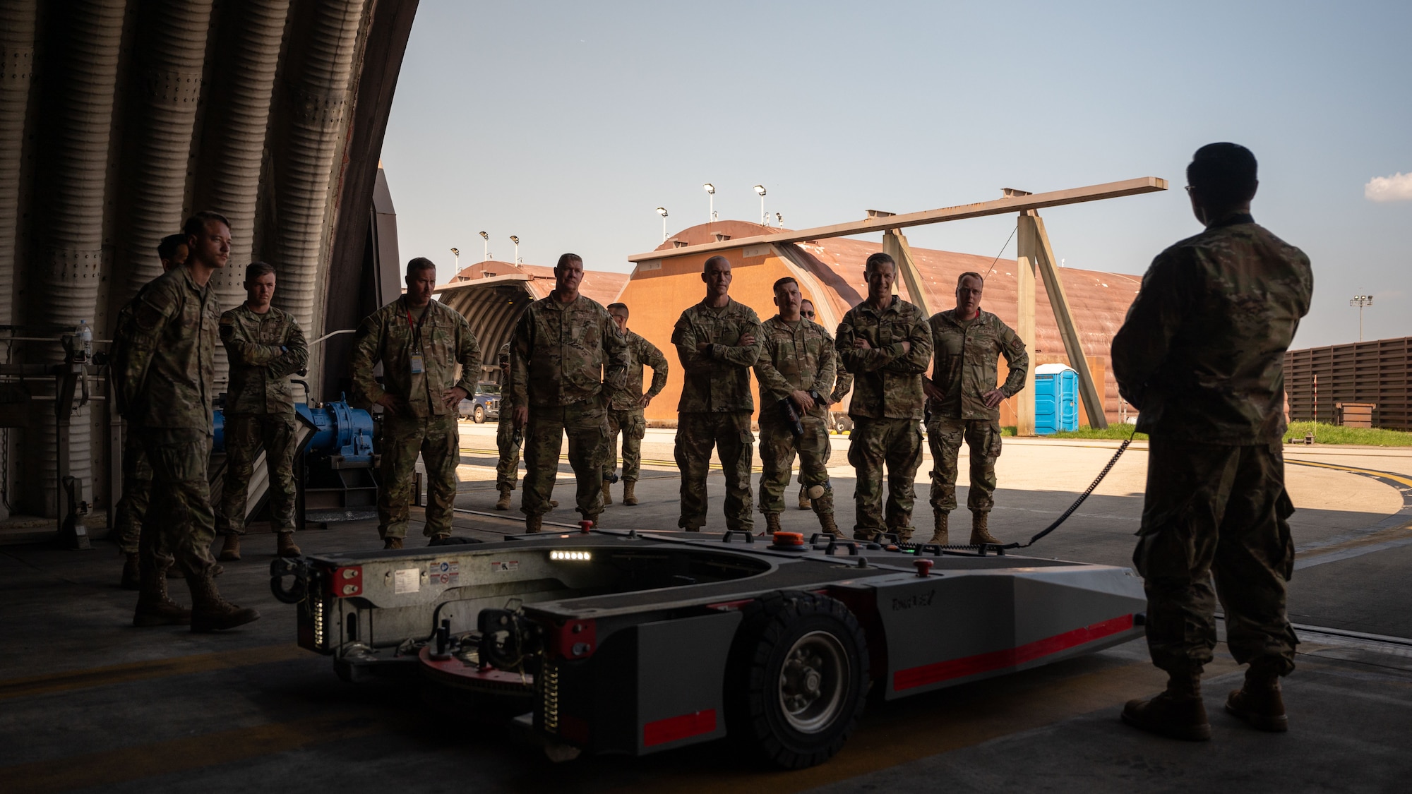 U.S. Air Force Col. Ryan Ley, 51st Fighter Wing commander, and other service members, watch a towing demonstration at Osan Air Base, Republic of Korea, July 9, 2025. These F-16 Fighting Falcon tow machines are capable of performing quick maneuvers, and can tow F-16s much quicker than the previous equipment used before. (U.S. Air Force photo by Senior Airman Rome Bowermaster)