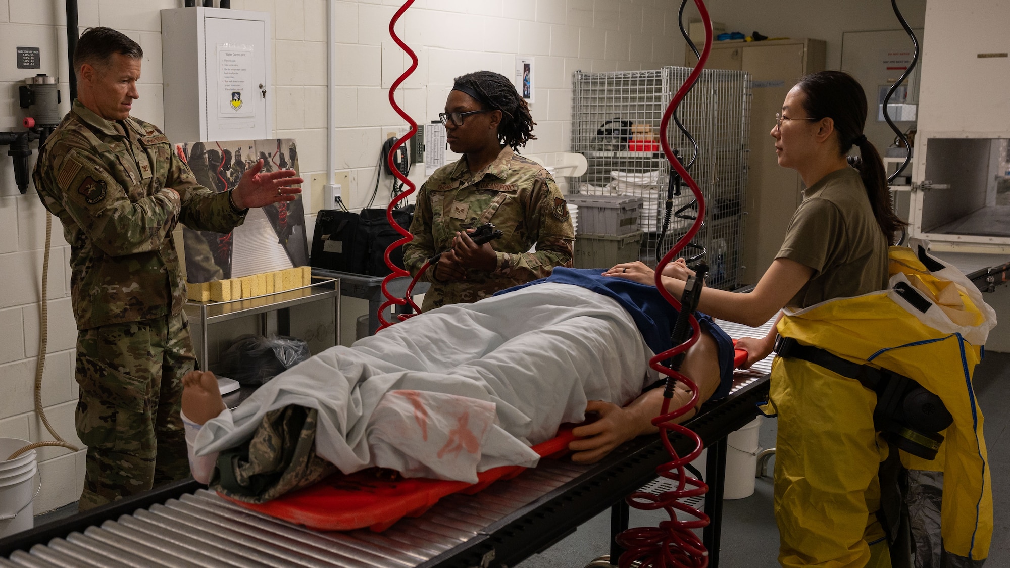 U.S. Air Force Col. Ryan Ley, left, 51st Fighter Wing commander, speaks with Senior Airman Terra Thomas, center, 51st Operational Medical Readiness Squadron dental assistant, and Staff Sgt. Hyun Mung Seo, right, 51st OMRS dental lab technician, at Osan Air Base, Republic of Korea, July 15, 2025. The airtight decontamination room is used in the event if a patient has any chemical exposure and needs to be decontaminated before any treatment is received to prevent further contamination. (U.S. Air Force photo by Senior Airman Rome Bowermaster)