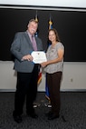 Timothy Ori, executive director of the 37th Training Wing, presents Anita Conder a certificate during her retirement ceremony.