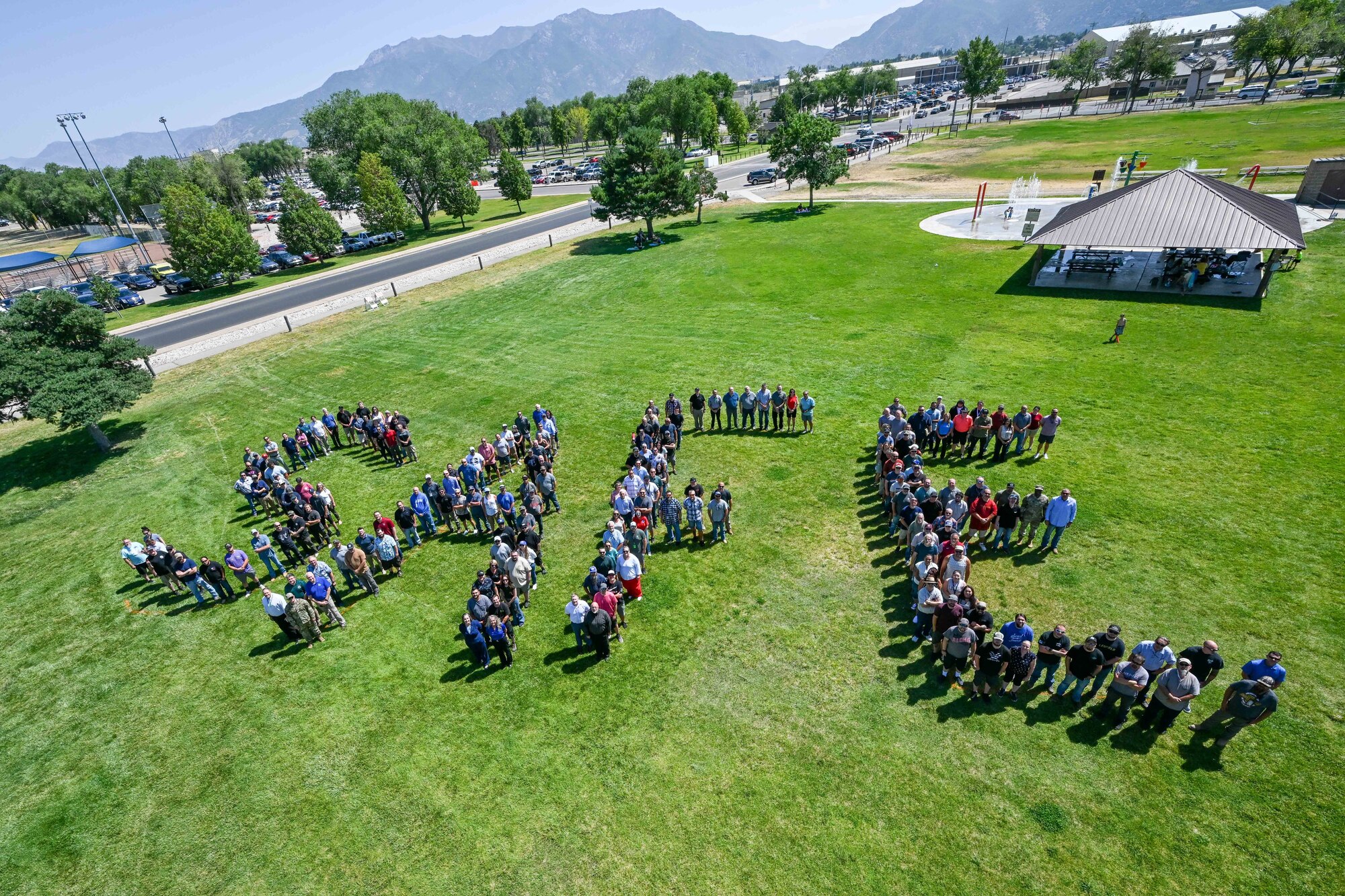 A large group of employees from the 309th Maintenance Support Group stands in a grassy field, arranged to spell the word “SAFE.”