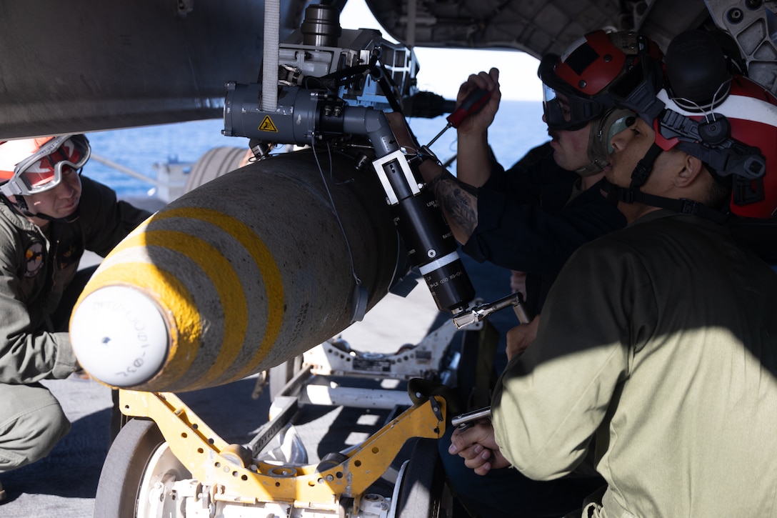 U.S. Marines with Marine Fighter Attack Squadron (VMFA) 242, 31st Marine Expeditionary Unit, load a GBU-32 Joint Direct Attack Munitions (JDAM) bomb, into the weapons bay of a F-35B Lightning II aircraft assigned to VMFA 242 during an ordnance load as a part of Talisman Sabre 25, aboard the amphibious assault ship USS America (LHA 6), in the Coral Sea, July 14, 2025. Marines with VMFA 242 arm F-35Bs with multi-discipline strike capabilities to support combined-joint all domain operations in key maritime terrain. Talisman Sabre is the largest bilateral military exercise between Australia and the United States advancing a free and open Indo-Pacific by strengthening relationships and interoperability among key allies and partners, while enhancing our collective capabilities to respond to a wide array of potential security concerns. (U.S. Marine Corps photo by Sgt. Peter Rawlins)