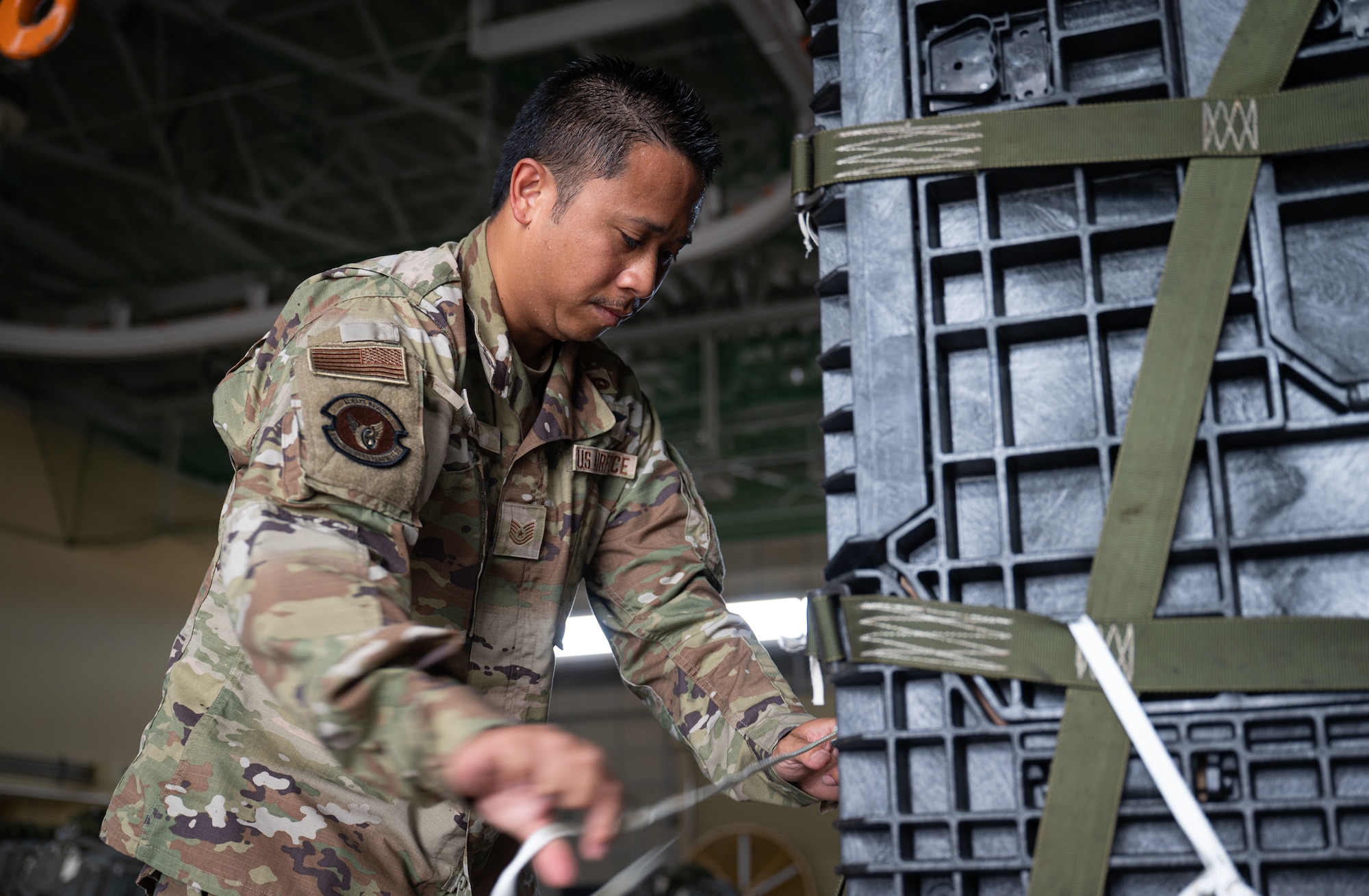 A military member ties a strap on a cargo bundle.