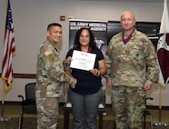 Liz Serra shakes hands with Col. Joselito “Joe” Lim, commander of the U.S. Army Medical Materiel Agency, following her induction into the Order of Military Medical Merit during a quarterly town hall July 10 at Fort Detrick, Maryland. Also pictured is USAMMA Sgt. Maj. Todd Brenecki. Serra, a 15-year Army veteran, has served in USAMMA’s Distribution Operations Center (DOC) for nearly a decade and led the DOC’s vaccine distribution efforts during the COVID-19 pandemic response.