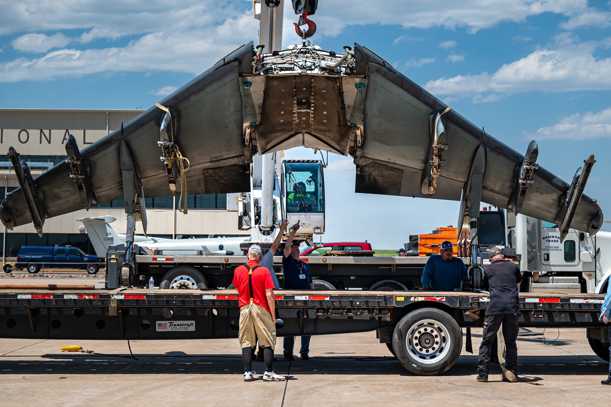 men lift wing plan onto truck