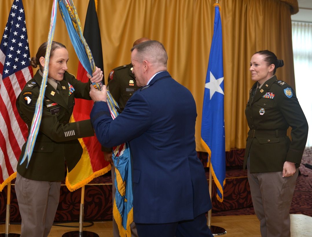 Maj. Gen. David Sanford passes a flag with the unit colors to U.S. Army Col. Tracy Yates, with Col. Adrian J. Sullivan looking on in the background