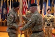 Maj. Gen. Eric P. Shirley, outgoing commanding general, 1st Theater Sustainment Command, passes the unit guidon to Brig. Gen. John “Brad” Hinson, incoming commanding general, 1st TSC, during the change of command ceremony at Fort Knox, June 26, 2025.