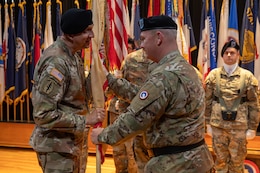 Maj. Gen. Eric P. Shirley, outgoing commanding general, 1st Theater Sustainment Command, passes the unit guidon to Brig. Gen. John “Brad” Hinson, incoming commanding general, 1st TSC, during the change of command ceremony at Fort Knox, June 26, 2025.
